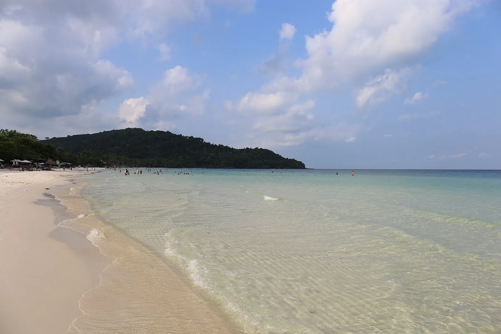White sand and shallow turquoise water at Bai Sao beach on Phu Quoc, with a forested headland behind