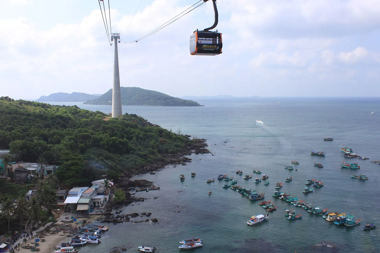 A Hon Thom cable car cabin and pylon above An Thoi harbour, its fishing boats and the southern islands of Phu Quoc