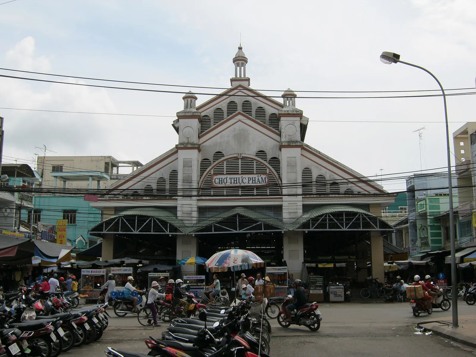 The arched facade of Sa Dec market with motorbikes parked in front