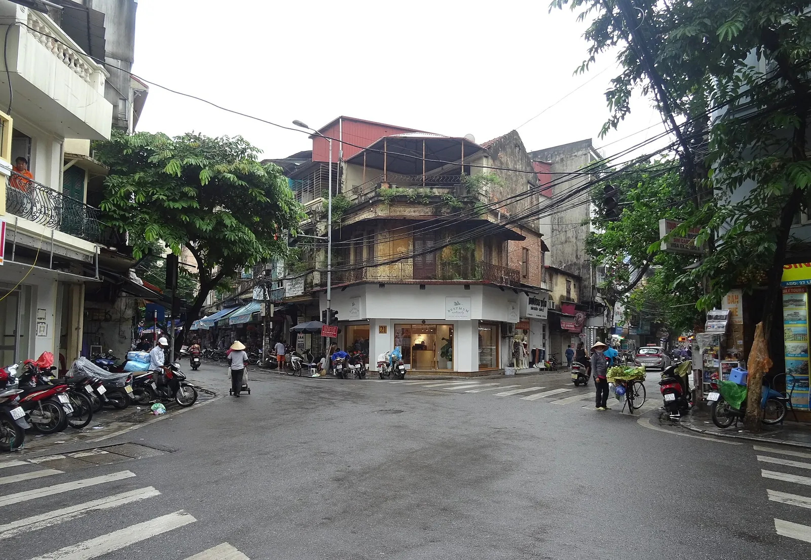 A street corner in Hanoi's Old Quarter where Lãn Ông, Hàng Cân and Chả Cá streets meet, with parked motorbikes along the pavement
