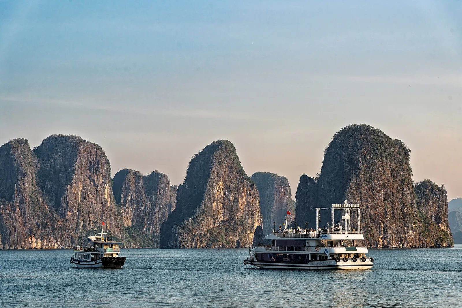 Tourist boats on the water in front of limestone karst islands in Ha Long Bay
