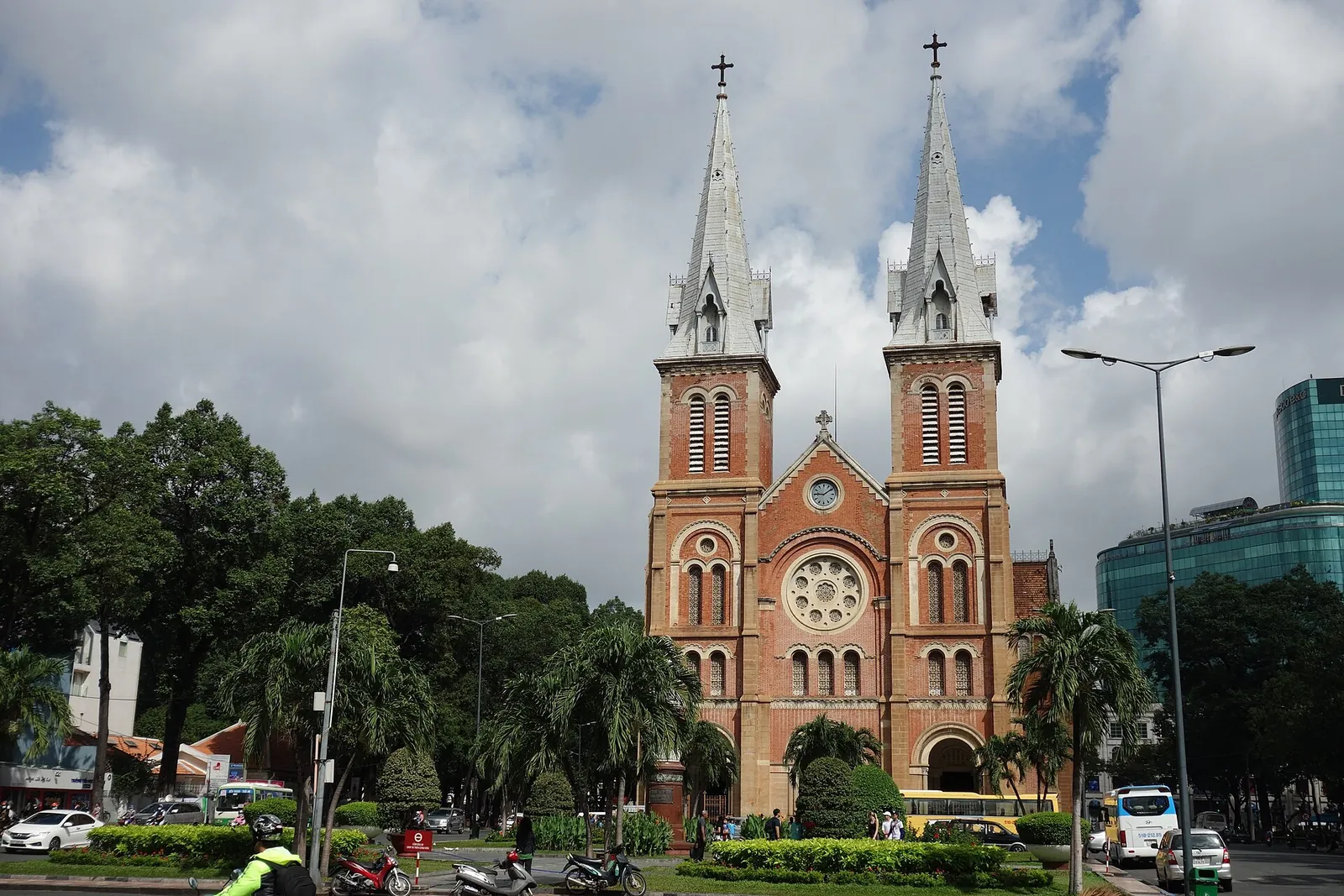 The red-brick twin spires of Saigon Notre-Dame Cathedral behind trees and the square in front