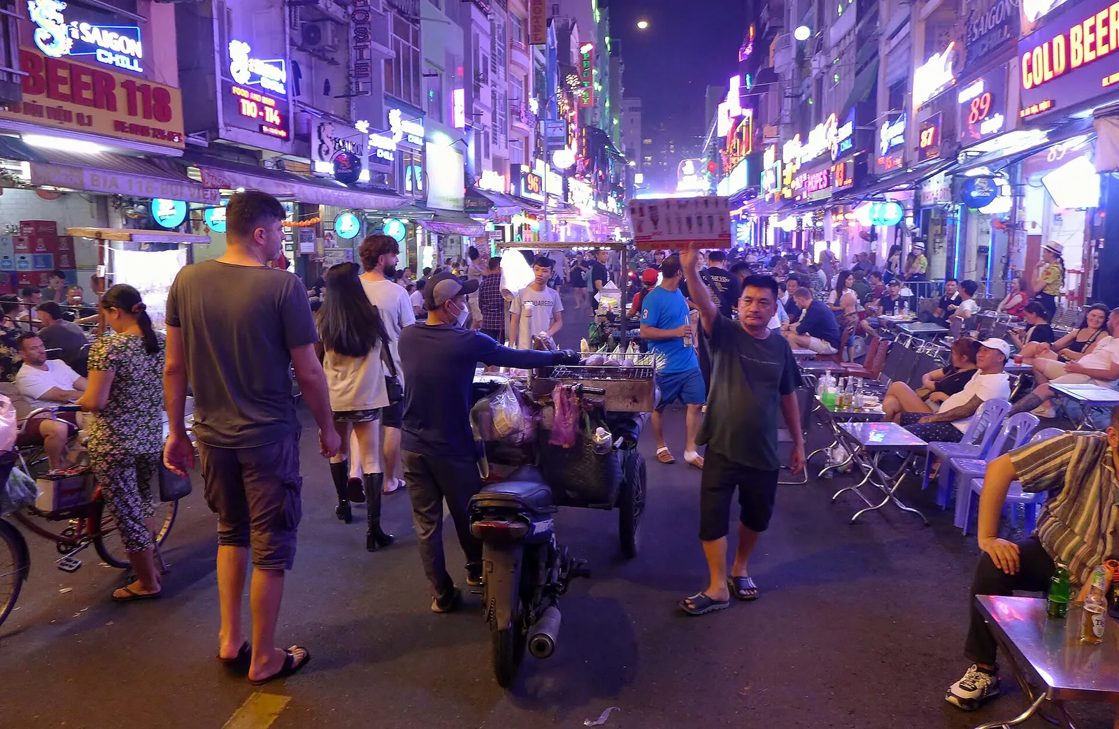 Crowds, street vendors and neon bar signs on Bui Vien Street at night