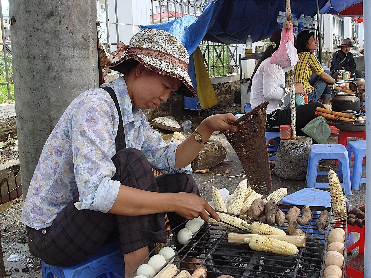 A street vendor in Sa Pa grilling corn and sweet potatoes over a charcoal grill