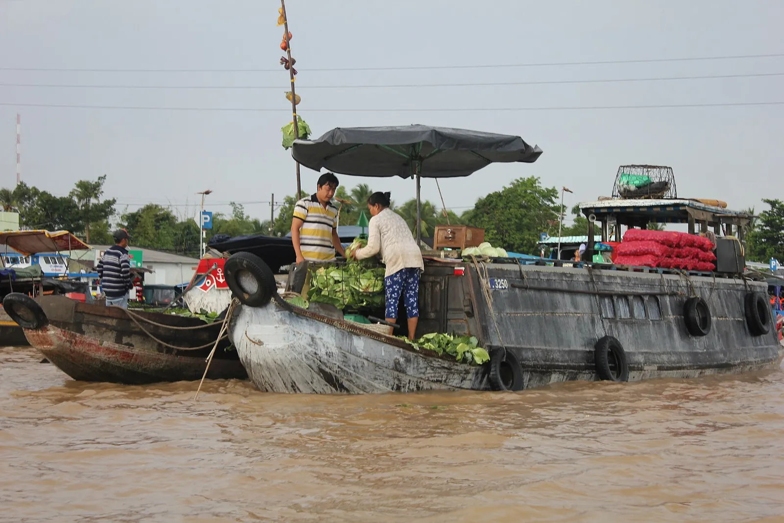 Traders on wooden boats loaded with vegetables at a floating market in Can Tho on the Mekong Delta
