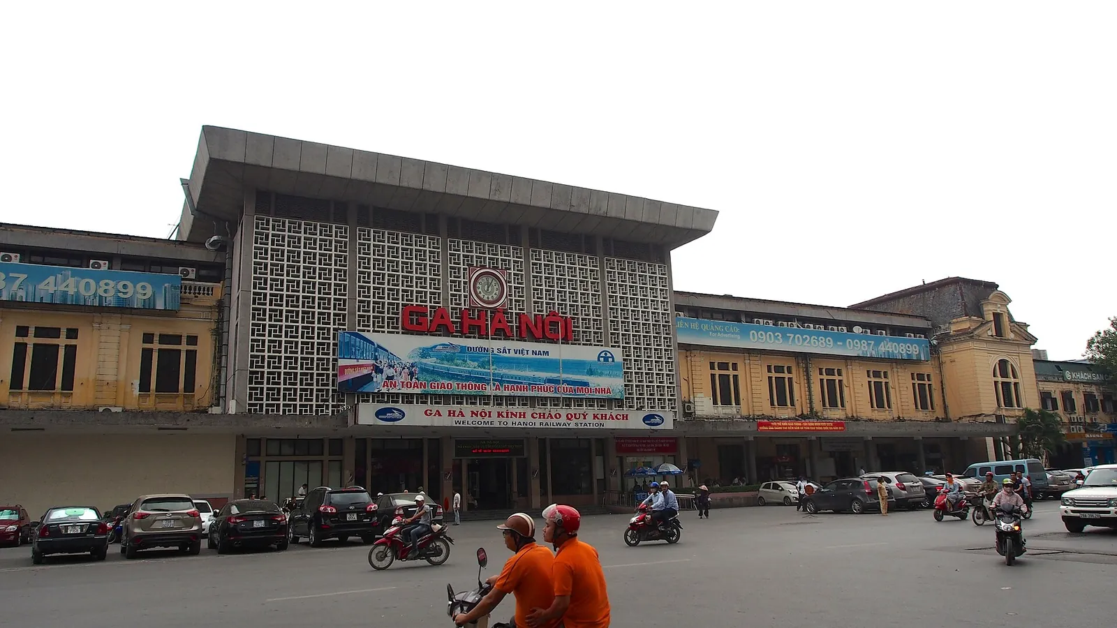 The white facade of Hanoi Railway Station with its red Ga Hà Nội sign, cars and motorbikes in front