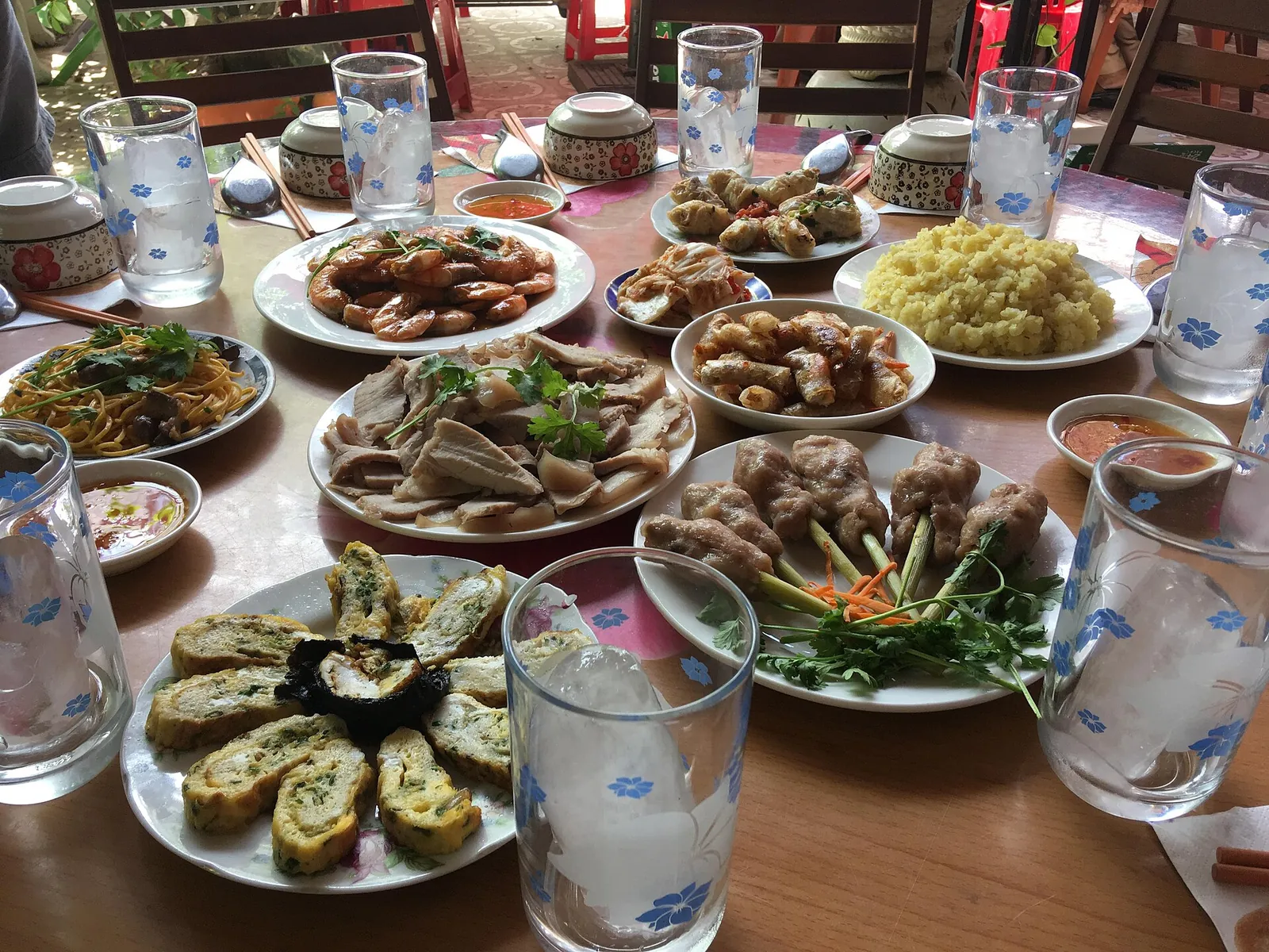 A table in Tuy Hoa set with plates of local dishes, rolls and dipping sauces