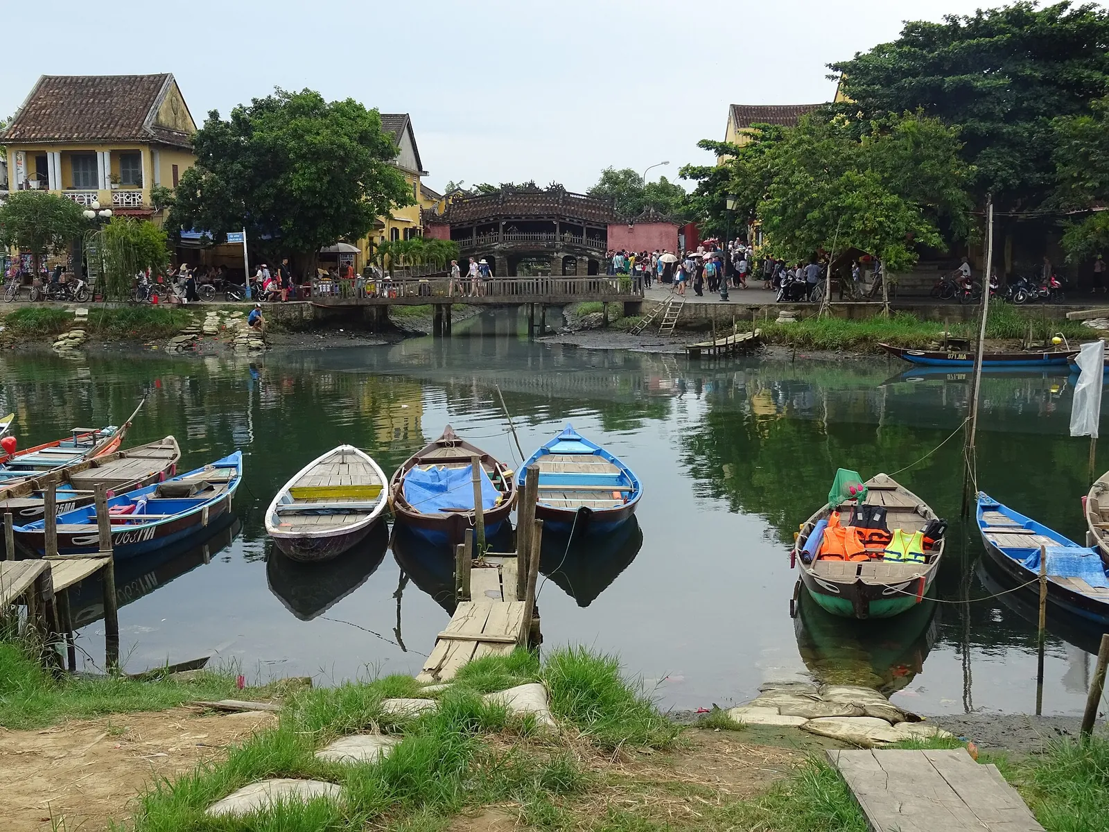 Small boats moored in a creek in Hoi An with the Japanese Covered Bridge and old houses behind