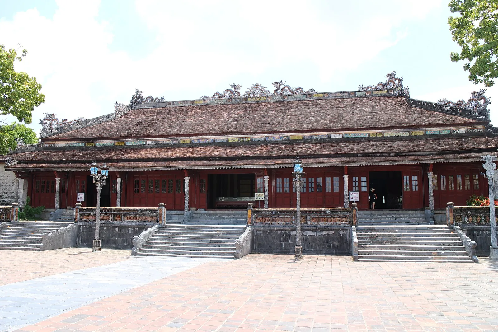 A red-pillared royal hall with a tiled roof behind a paved courtyard in Hue's Imperial City