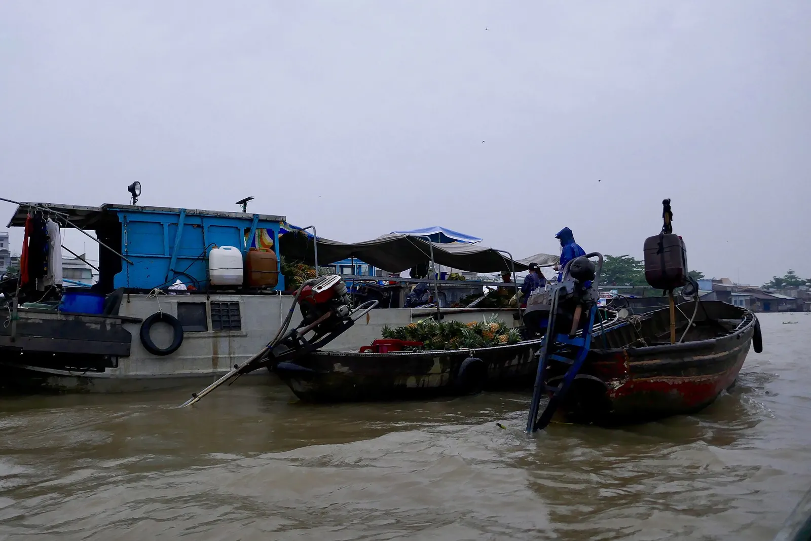 Wooden trading boats moored on the wide brown river at the Cai Rang floating market