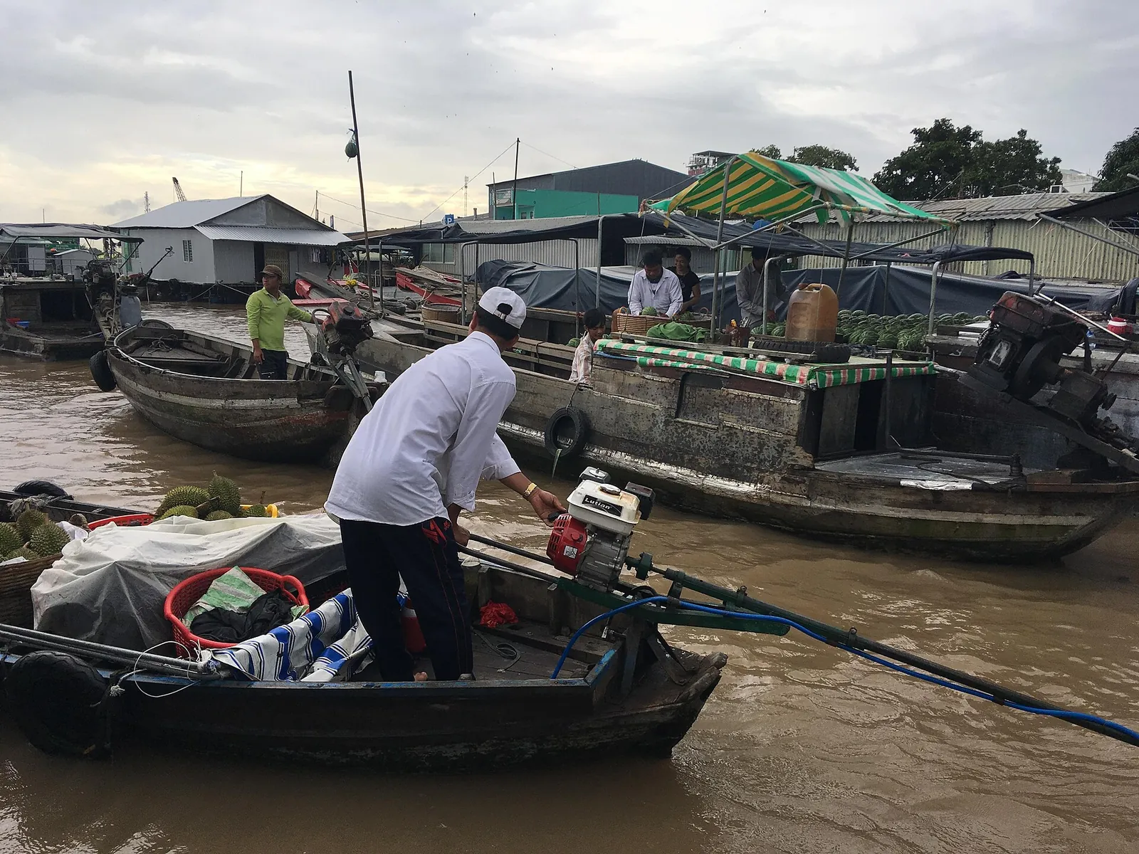 Wooden boats laden with produce on the brown river at Cai Rang floating market