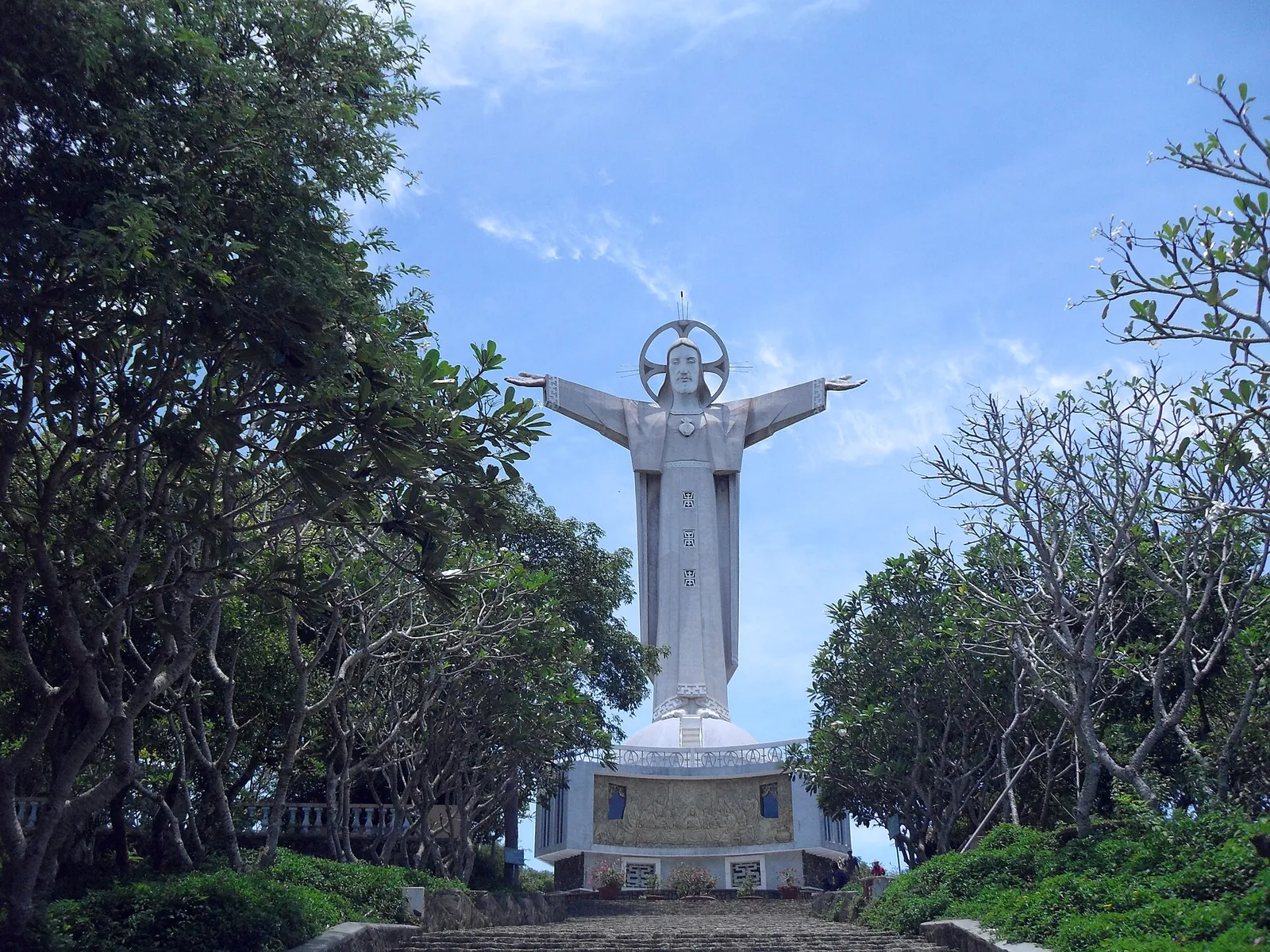 The white statue of Christ the King with outstretched arms on Small Mountain, framed by trees