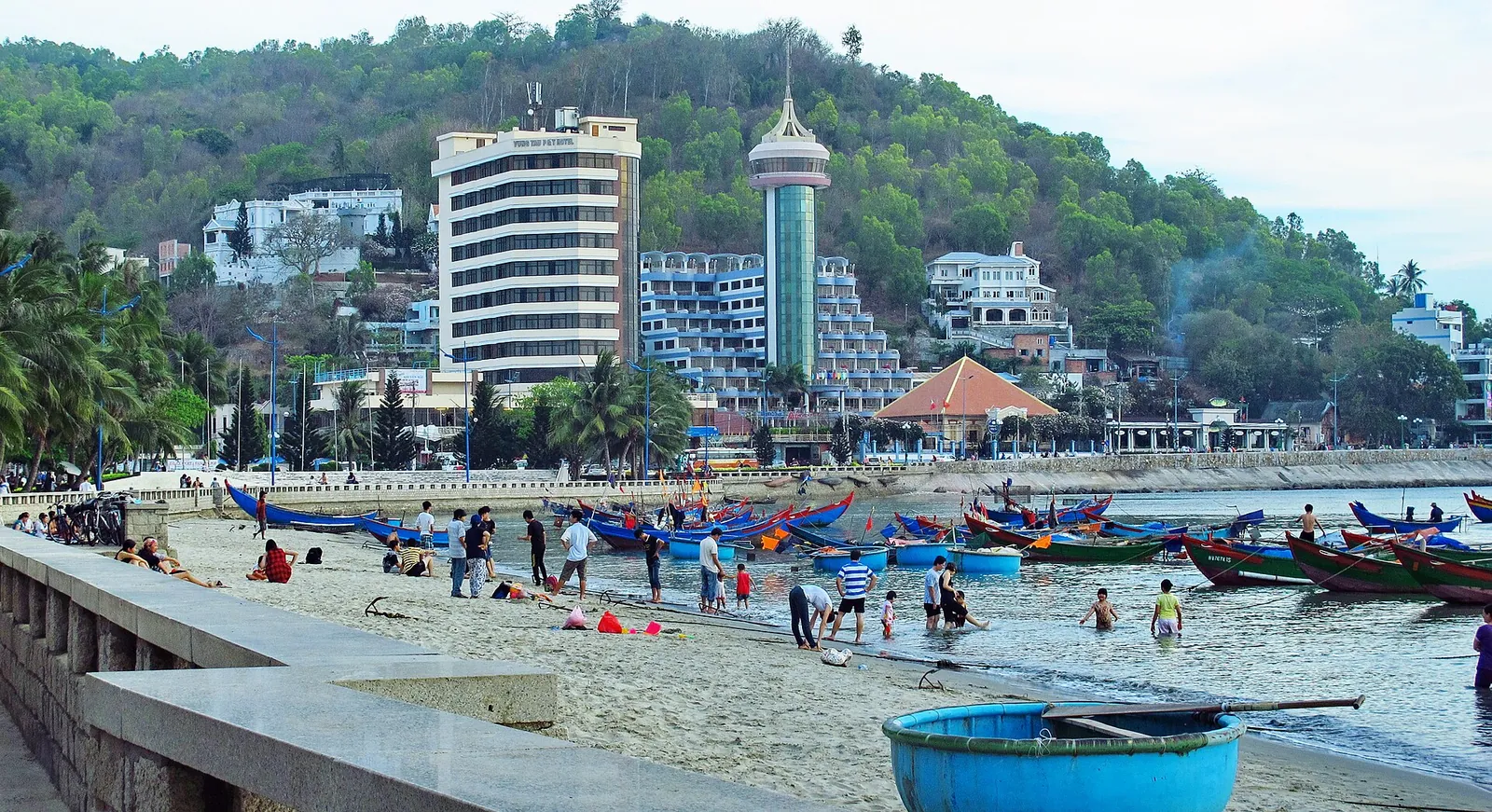 Basket boats and fishing boats pulled up on Front Beach with hotels and Small Mountain behind
