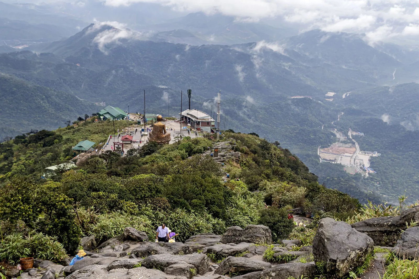 Rocky summit ridge of Yen Tu Mountain with pagoda buildings and forested ranges behind