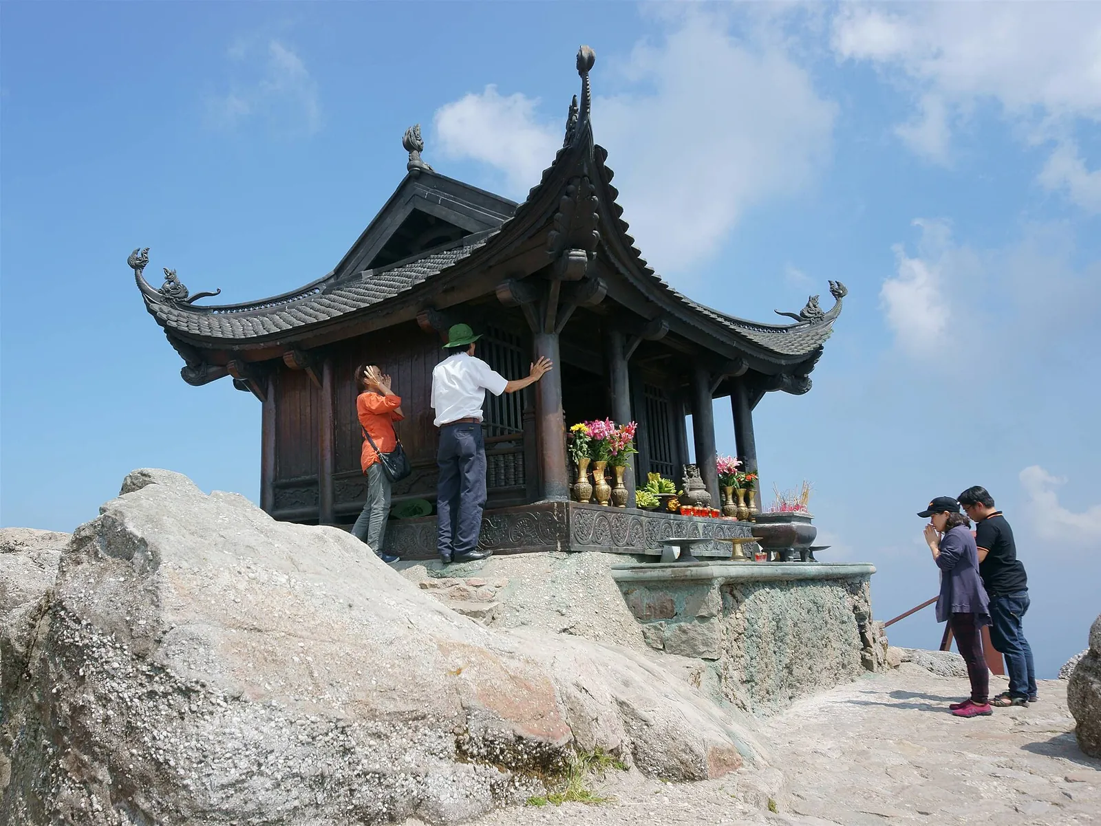 The small bronze Dong Pagoda on a granite outcrop at the top of Yen Tu under a blue sky